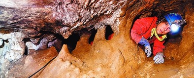 El estadounidense Rolf Quam pasa por la gatera, uno de los puntos más estrechos de la Cueva Mayor. DB/Alberto Rodrigo
