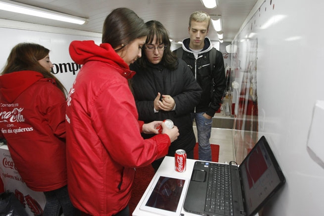 El autobús de la Coca-Cola, con gente poniendo etiquetas en las latas