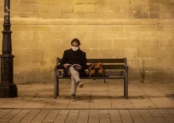 Imagen de un joven leyendo en un banco de la calle portales de Logroño